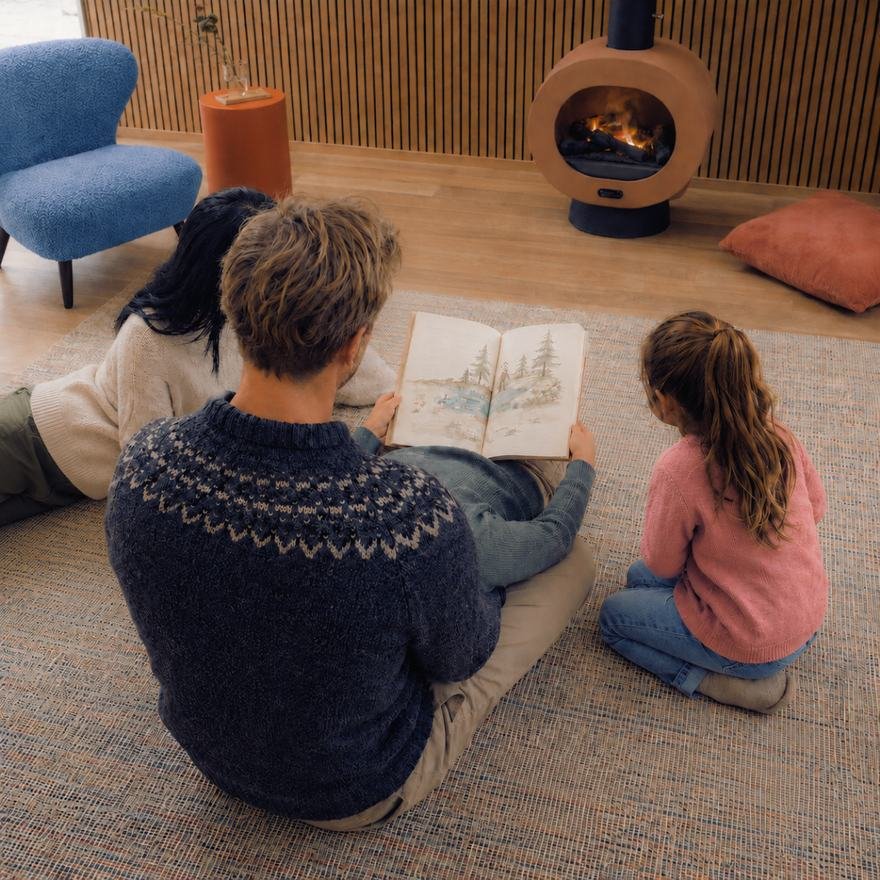 A grown-up and a child on the floor with an open book between them.